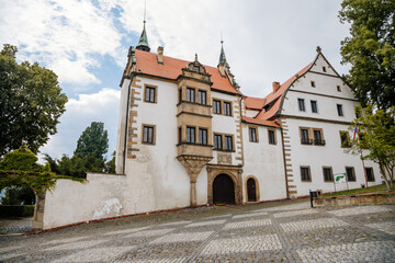 Benesov nad Ploucnici, North Bohemia, Czech Republic, 26 June 2021: old saxoxy renaissance Morzinov Castle near Town Hall at summer sunny day, graceful towers with spiers, green trees at the street