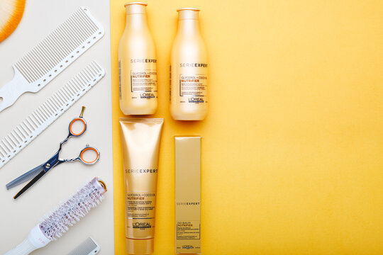 L'oreal professionnel Paris Serie Expert loreal nutrifier hair professional products set scissors combs and hairdressing tools. Loreal hair shampoo on color background. Gold cosmetics bottles.Top view