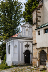 Fototapeta premium Benesov nad Ploucnici, North Bohemia, Czech Republic, 26 June 2021: old gothic church of the Nativity of the Virgin Mary with stone towers near old saxoxy renaissance castle at summer sunny day