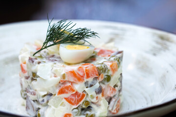 Russian traditional salad Olivier with vegetables and meat. Salad on a plate