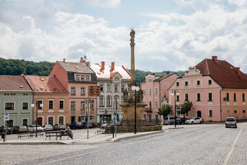 Benesov nad Ploucnici, North Bohemia, Czech Republic, 26 June 2021: Marian Column with baroque statues at main town square, old baroque historic buildings and Town Hall at summer sunny day