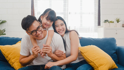 Happy cheerful Asian family dad, mom and daughter having fun cuddling and video call on laptop on...