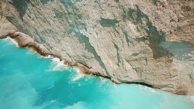 4K Aerial footage of stunning white rocks and turquoise clean water near to Navagio beach known as Shipwreck Beach or Shipwreck Cove located in Zakynthos island, Greece.