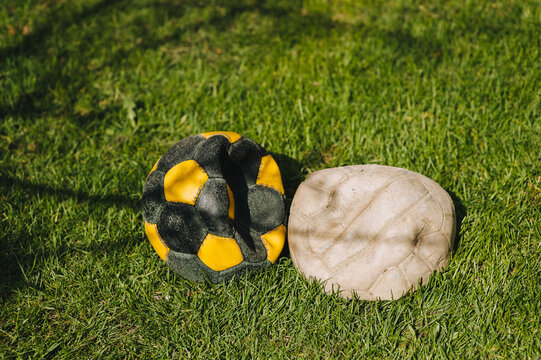 Two lowered football old multi-colored balls lie on the green grass of the sports field. Photo of the match.