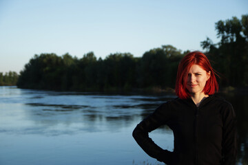 girl with red hair on the background of the river and forest
