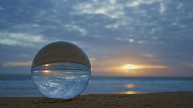 The natural view of the sea and sky in beautiful sunset are unconventional and beautiful inside crystal ball. .A image for a unique and creative travel.
