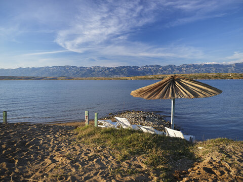 Umbrella and folding chairs on a beach surrounded by the sea on a sunny day in Vrsi, Croatia