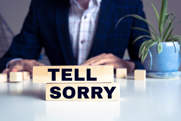 An image of letter imprinted wood blocks displaying the words - TELL SORRY.