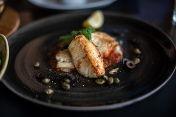 Grilled sea bass with lime served on black plate.