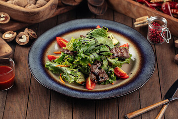 Salad with warm veal and greens on the wooden background