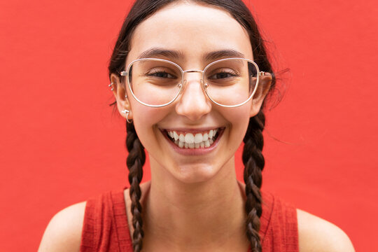 Happy woman with pigtails on red background in city