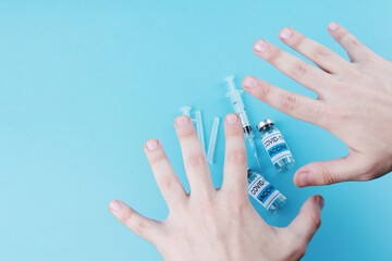 The hands of a young man, vials of vaccine and syringes on a blue medical background. The concept...