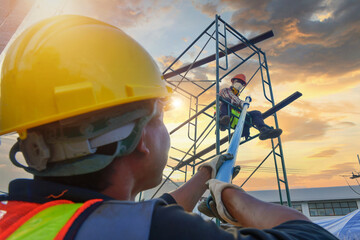 Construction worker wearing safety work at high uniform on scaffolding at construction site on...