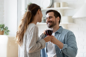 Romantic relationships, proposal, relocation day, events celebrations concept. Young couple in love holding wineglasses, clinking glasses of red wine enjoy dating in modern kitchen rented or own home