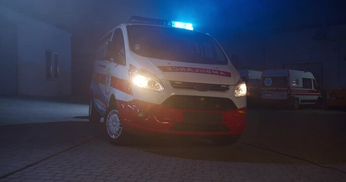 Ambulance car with blue and red lights at street in dark evning. Paramedical vehicle at city outdoors at night shift. Automobile of medics in dark.