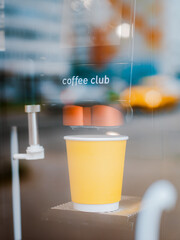 yellow paper cup is a drink in the morning through the glass by the highway.