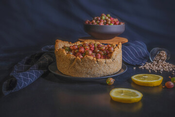 Open pie with wild gooseberry and lemon cream on dark wooden background. Rustic photography.