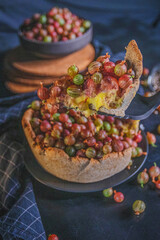 Open pie with wild gooseberry and lemon cream on dark wooden background. Rustic photography.