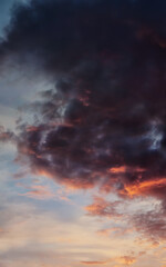 Dramatic sky with dark clouds illuminated with evening sun, vertical panorama.