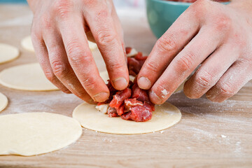 A man is holding a khinkali in close-up. Cook in the kitchen. The process of preparing a national dish.