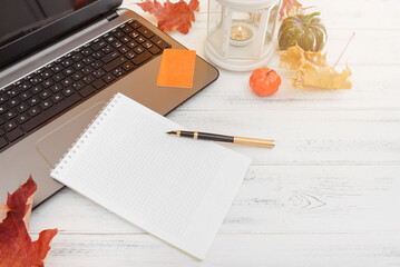 pen, notebook, laptop, pumpkin, leaves, candle on a white table