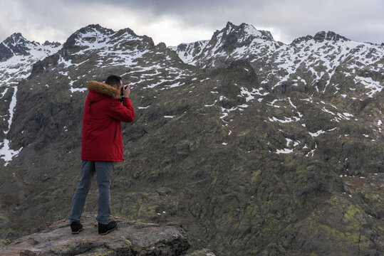 Male tourist taking photos of snowy mountains