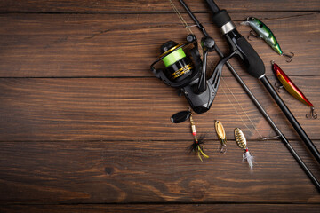 Fishing tackle - fishing spinning rod, hooks and lures on wooden background. Active hobby recreation concept.