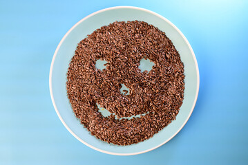flaxseeds in the shape of a smile on a blue plate against a blue background
