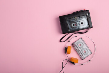 Music listening concept. Vintage cassette tape, audio player and headphones close-up on pink background, top view.