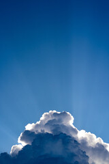 Rays of light shining through the cloud against blue sky background.