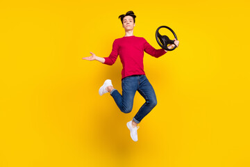 Fototapeta na wymiar Photo of sweet serious young gentleman wear red pullover jumping high holding steering wheel isolated yellow color background