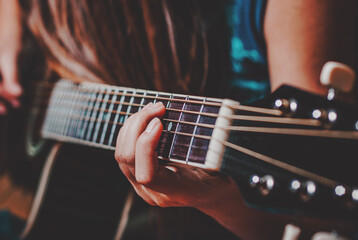 Closeup of young woman hand playing on black acoustic guitar