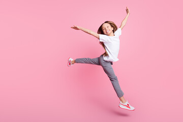 Full length body size view of pretty childish cheerful girl jumping having fun isolated over pink...