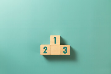 Wooden podium standing with the number 1 2 3 on green background. Concept of success,winner,...
