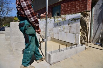 The mason on the construction site measures the perpendicularity of the walls with a spirit level