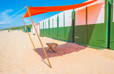 Green grassy dunes along the North Sea coast illuminated by the light of a colorful sun and a blue cloudy sky in summer, Walcheren, Zeeland, the Netherlands, July, 2021