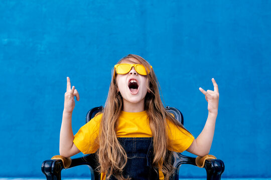 Cool teenager in sunglasses showing rock gesture