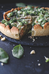 Millet quiche with spinach, salmon, broccoli and ricotta on dark wooden table. Homemade 
vegetarian cake. Copy space for text. Fresh pie with soft cheese. Healthy food. French cuisine