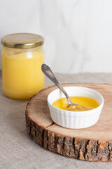 Ghee clarified butter desi in glass jar on wood slice. 