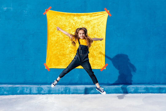 Excited teenager jumping against yellow and blue background