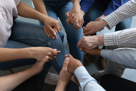 Group of anonymous addicted prayers holding hands, praying on therapy meeting, giving empathy, support, help, expressing compassion , trust, understanding, keeping community spirit. Close up