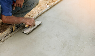 Hand of worker use trowel plastering a newly poured concrete on construction site