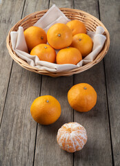 Mini tangerines in a basket over wooden table