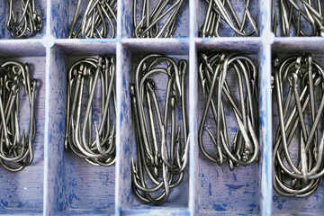 Top view of tackle box with fishing hooks. Fishing hooks in box sections. Macro of fishhooks