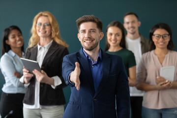 Happy confident businessman, business leader, employer offering handshake at camera with diverse...