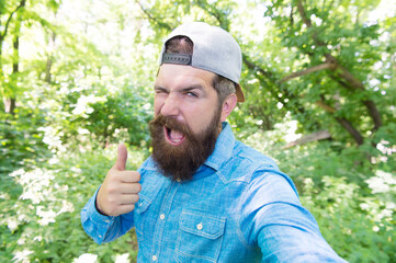 happy mature bearded man with beard make selfie photo in summer forest show thumb up, joy