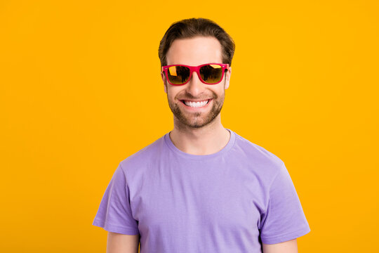 Photo of cheerful traveler guy toothy beaming smile wear sunglass purple t-shirt isolated yellow color background