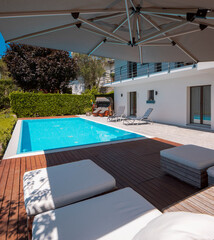 Large modern pool with two sun loungers for sunbathing and an open umbrella. View of the mountains...