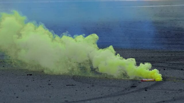 A colored yellow smoke bomb lies on the asphalt and smokes during the car drift racing competitions. Motorsport championship. Closeup. Professional extreme drive