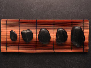 Five massage stones on a bamboo mat